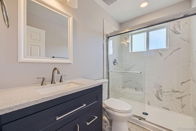 bathroom featuring vanity, a shower with shower door, and toilet