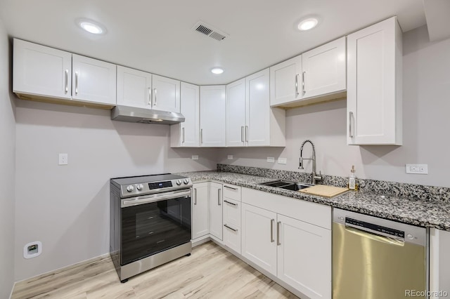 kitchen featuring sink, light hardwood / wood-style flooring, stainless steel appliances, white cabinets, and dark stone counters