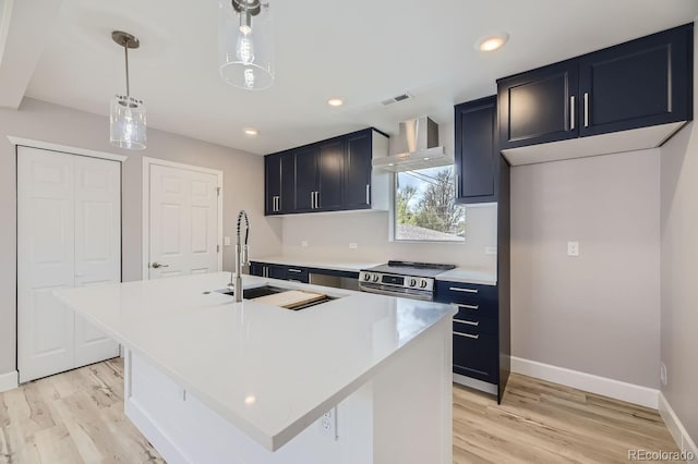 kitchen with sink, stainless steel electric range, hanging light fixtures, a center island with sink, and wall chimney exhaust hood