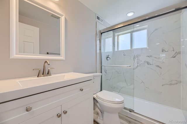 bathroom featuring vanity, toilet, and a shower with shower door