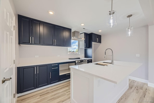 kitchen with pendant lighting, sink, stainless steel range with electric stovetop, a center island with sink, and wall chimney exhaust hood