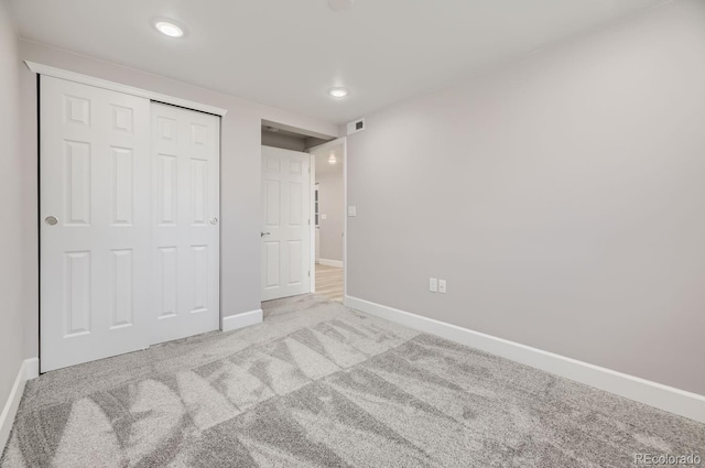 unfurnished bedroom with light colored carpet and a closet