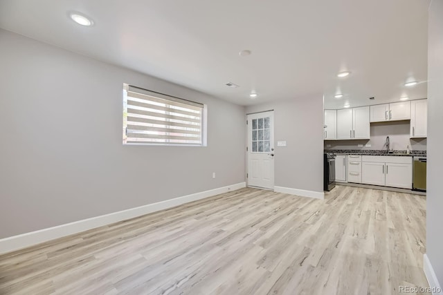 unfurnished living room featuring sink and light hardwood / wood-style floors