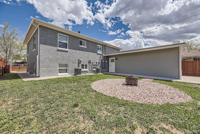 rear view of house featuring central AC unit, a fire pit, and a lawn