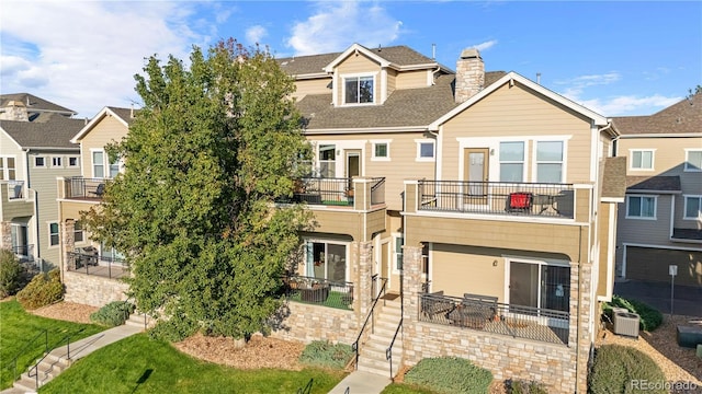 rear view of house featuring a balcony, a chimney, fence, and a patio