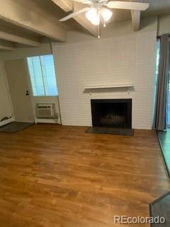 unfurnished living room featuring a wall mounted air conditioner, ceiling fan, beamed ceiling, and hardwood / wood-style flooring