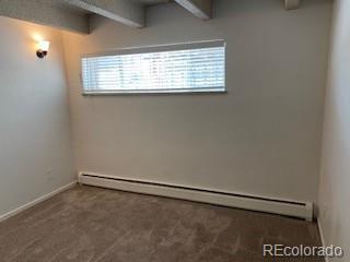 carpeted spare room featuring beamed ceiling and a baseboard heating unit