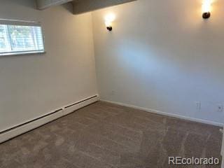 basement featuring a baseboard heating unit and dark colored carpet