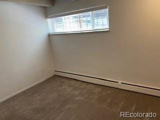 carpeted empty room with a baseboard heating unit