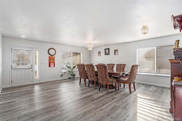 dining room with a wealth of natural light, a textured ceiling, baseboards, and wood finished floors