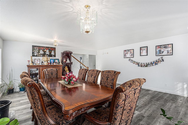 dining room featuring a chandelier, stairway, baseboards, and wood finished floors