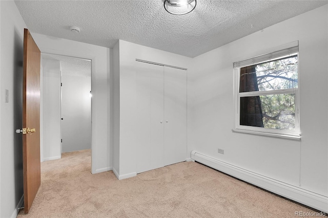 empty room with a textured ceiling, light colored carpet, and a baseboard radiator