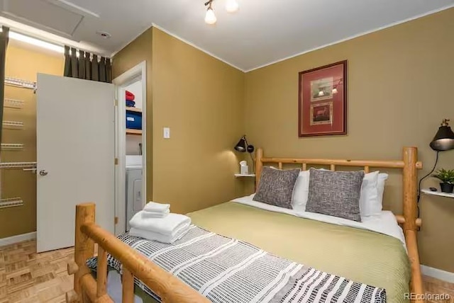 bedroom with washer / clothes dryer and light parquet flooring