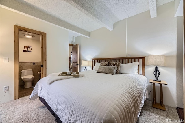 carpeted bedroom with ensuite bathroom, a textured ceiling, and beam ceiling