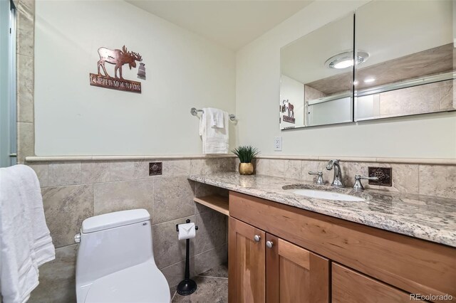 bathroom featuring vanity, toilet, and tile walls