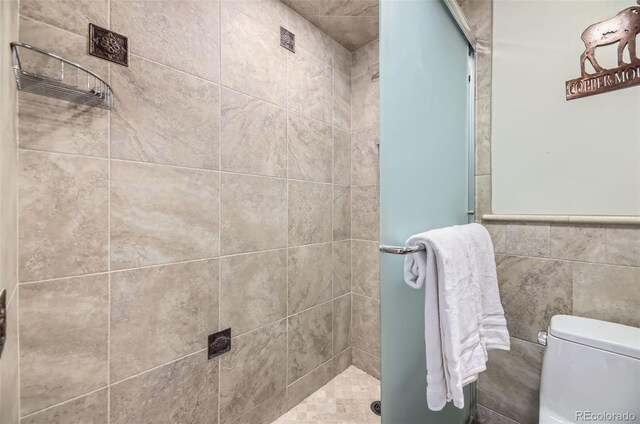 bathroom with tile walls, toilet, and a shower with shower door