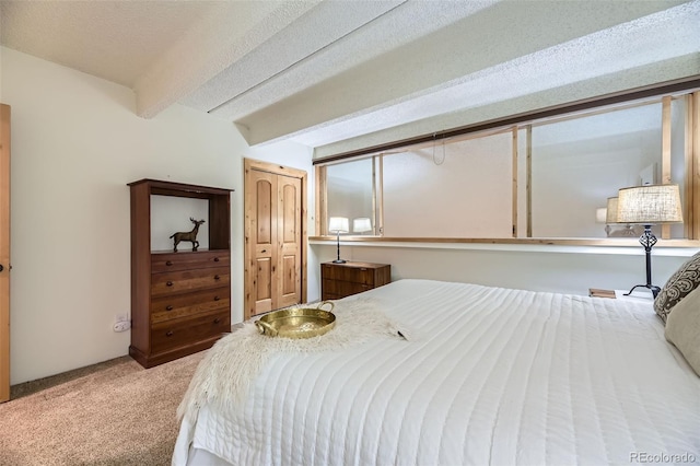 carpeted bedroom with a closet, a textured ceiling, and beam ceiling