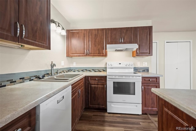 kitchen featuring a sink, dark wood-style floors, under cabinet range hood, light countertops, and white appliances