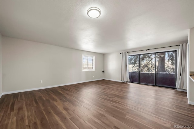 unfurnished room with baseboards and dark wood finished floors