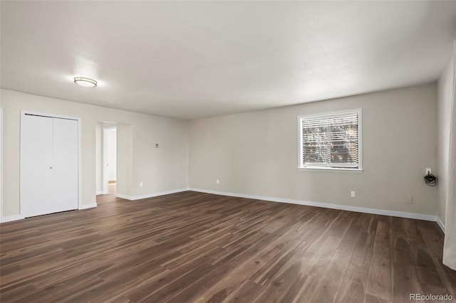 spare room featuring baseboards and dark wood-style floors