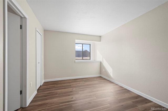 spare room with baseboards and dark wood-style floors