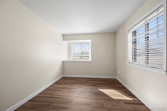 unfurnished room with baseboards and dark wood-type flooring