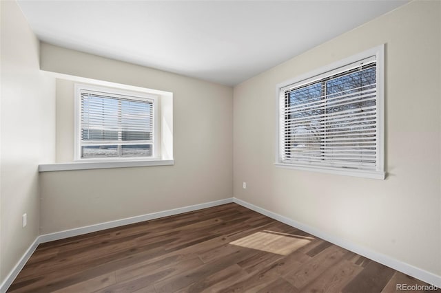 empty room featuring baseboards and dark wood-type flooring