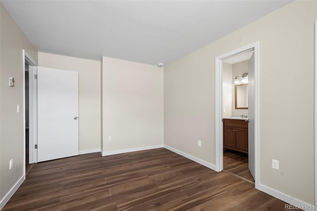 unfurnished bedroom with baseboards, ensuite bath, and dark wood-style flooring