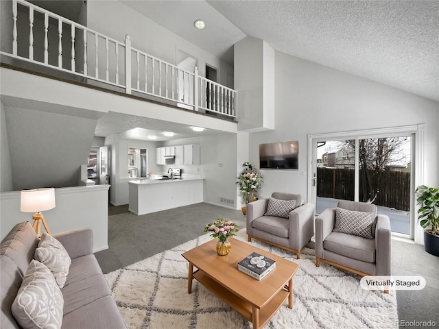 living room featuring a textured ceiling, high vaulted ceiling, and sink