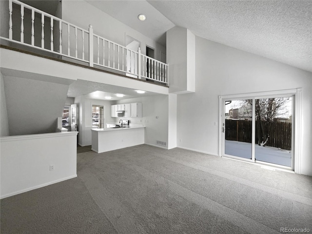 unfurnished living room with a textured ceiling, dark carpet, and a healthy amount of sunlight