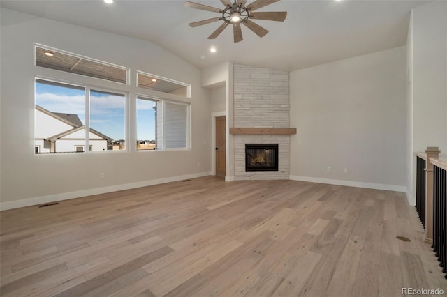 unfurnished living room with vaulted ceiling, a stone fireplace, ceiling fan, and light hardwood / wood-style floors