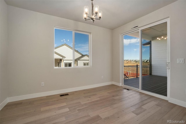 unfurnished room with light hardwood / wood-style floors and a notable chandelier