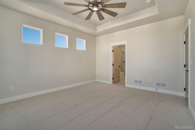 carpeted empty room featuring a raised ceiling and ceiling fan