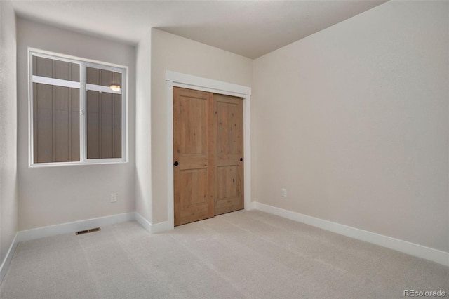 unfurnished bedroom featuring light carpet and a closet