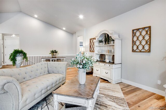 living room featuring light wood-type flooring and vaulted ceiling