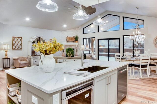 kitchen featuring an island with sink, hanging light fixtures, white cabinets, and light hardwood / wood-style floors