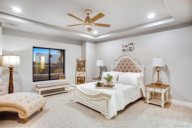 bedroom featuring ceiling fan, carpet floors, and a tray ceiling