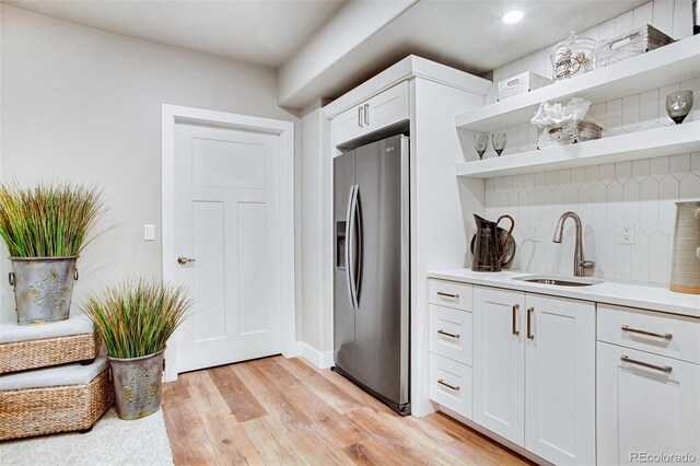 kitchen featuring white cabinets, stainless steel fridge, light hardwood / wood-style floors, and sink