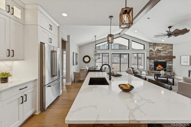 1361 Art Dr, Berthoud, CO 80513 - kitchen with high end refrigerator, a sink, a spacious island, vaulted ceiling, and light wood-style flooring