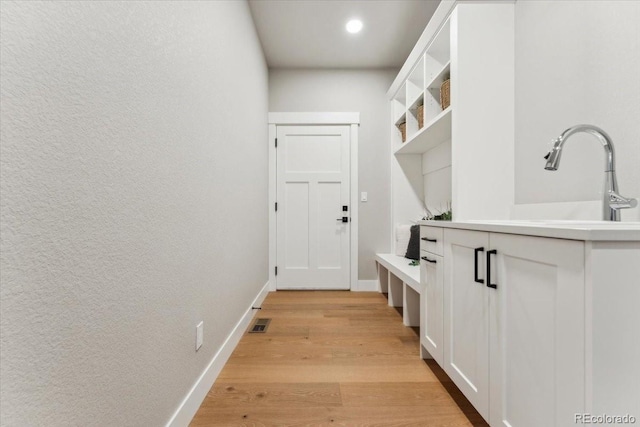 1361 Art Dr, Berthoud, CO 80513 - mudroom featuring light wood finished floors, baseboards, a sink, and a textured wall