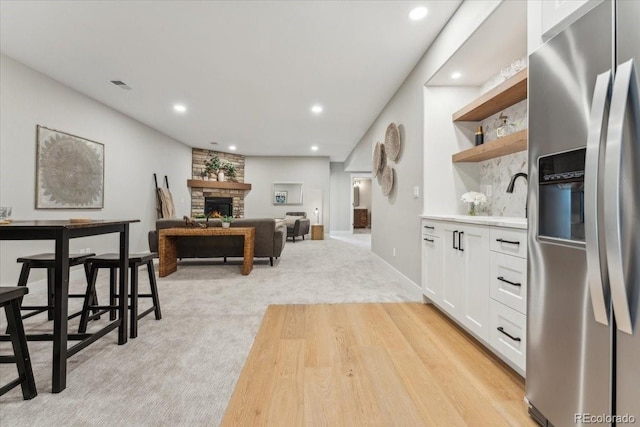 1361 Art Dr, Berthoud, CO 80513 - kitchen with stainless steel fridge with ice dispenser, white cabinets, open shelves, recessed lighting, and a stone fireplace