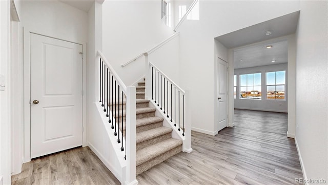 staircase featuring wood-type flooring and a towering ceiling