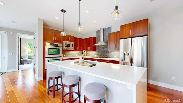 8041 E 29th Ave, Denver, CO 80238 - kitchen with stainless steel appliances, wall chimney range hood, tasteful backsplash, light wood finished floors, and recessed lighting
