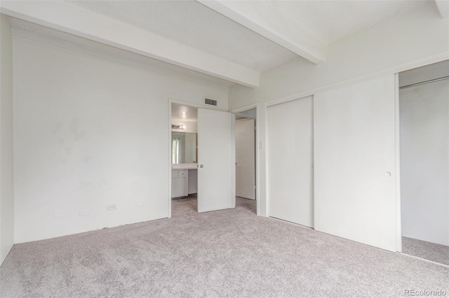 9725 E Harvard Ave Unit 317, Denver, CO 80231 - unfurnished bedroom featuring carpet, beam ceiling, and ensuite bathroom