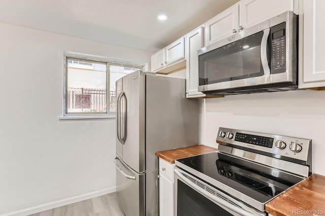 kitchen featuring white cabinetry, light hardwood / wood-style flooring, stainless steel appliances, and wood counters