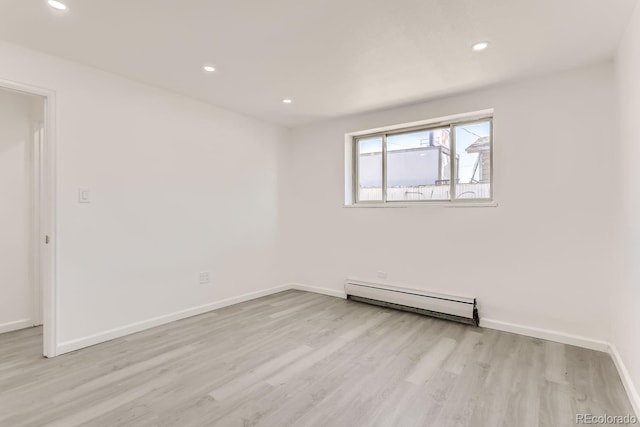 unfurnished room with a baseboard radiator and light wood-type flooring