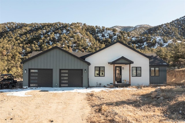 modern farmhouse featuring a garage, dirt driveway, and a mountain view