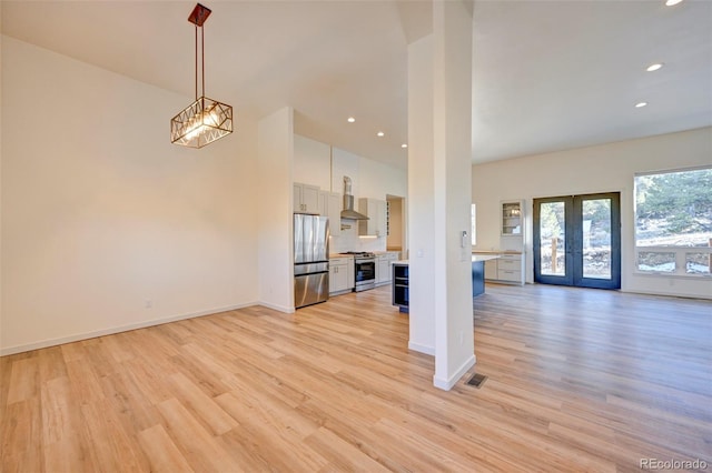 unfurnished living room featuring french doors, visible vents, light wood-style flooring, and baseboards