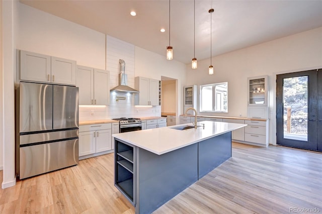 kitchen featuring a sink, appliances with stainless steel finishes, wall chimney exhaust hood, tasteful backsplash, and plenty of natural light