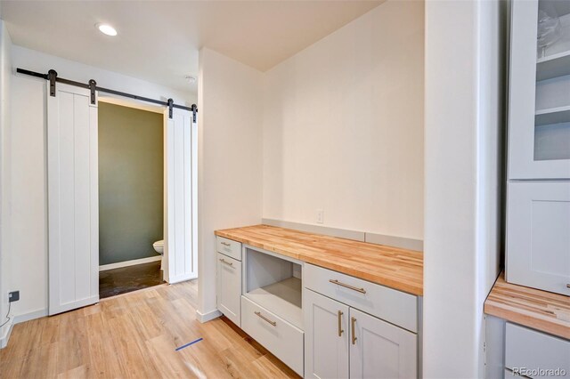 bathroom featuring baseboards, wood finished floors, toilet, and recessed lighting